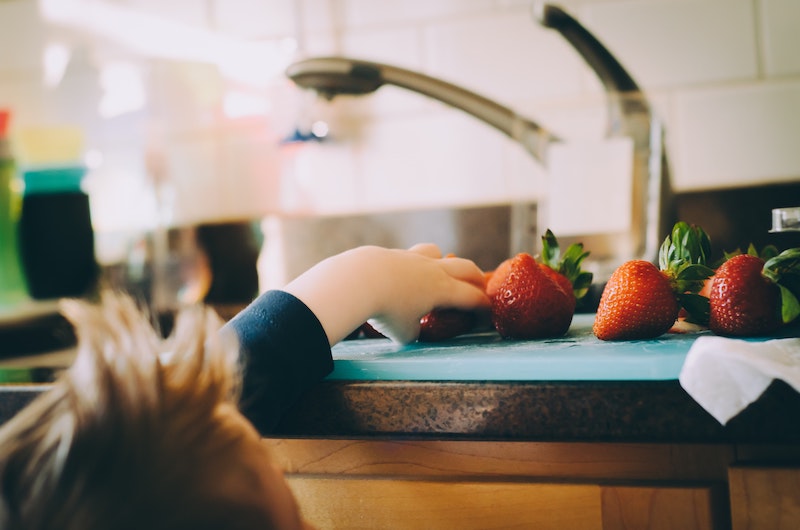 Child reaching for strawberries on counter