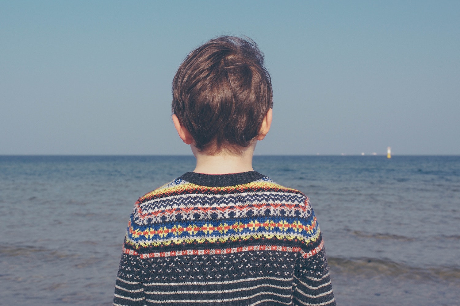 little boy standing in front of ocean